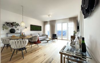 Modern eingerichtetes Wohnzimmer mit stilvollem Essbereich, großen Fenstern und edlem Parkettboden