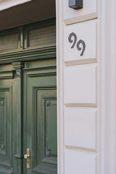 Detailaufnahme einer historischen Eingangstür mit kunstvoller Hausnummer und stilvoller Fassade