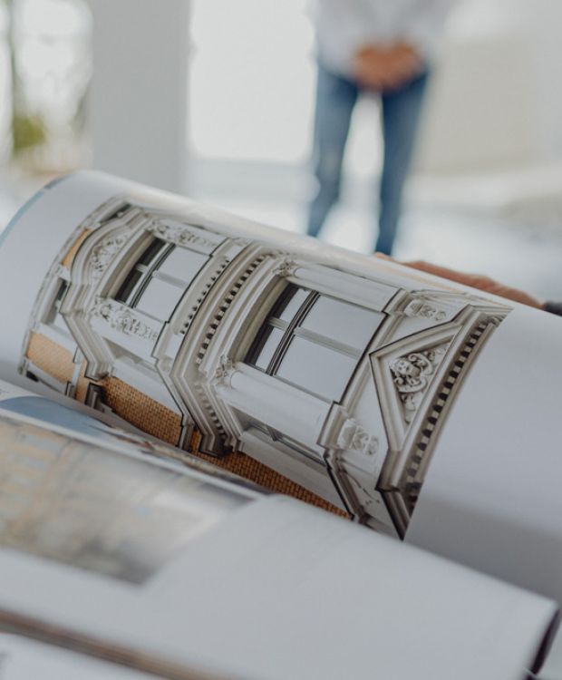 Aufgeschlagenes Immobilienbuch mit stilvoller Altbaufassade – Inspiration für hochwertige Wohnprojekte