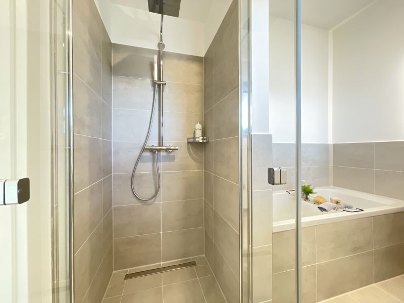 Modernes Badezimmer mit ebenerdiger Dusche, stilvollen Fliesen und einladender Badewanne zum Entspannen