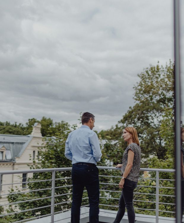 Beratungsgespräch auf der Terrasse mit Blick auf stilvolle Altbauten – Immobilienberatung in persönlicher Atmosphäre