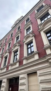 Sanierte Fassade eines Altbauhauses mit rotem Klinker und stilvollen Fenstern in zentraler Lage