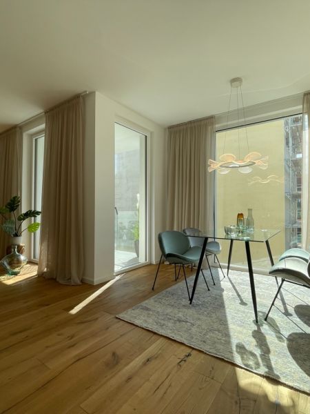 Großzügiges Wohnzimmer mit bodentiefen Fenstern, edlem Holzboden und stilvoller moderner Einrichtung