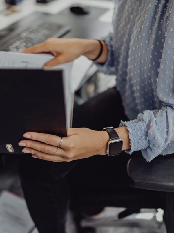 Mitarbeiterin im modernen Büro bei sorgfältiger Arbeit mit Unterlagen und Aktenordner