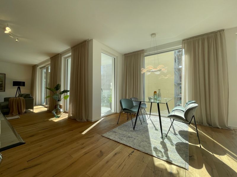 Großzügiges Wohnzimmer mit bodentiefen Fenstern, edlem Holzboden und stilvoller moderner Einrichtung