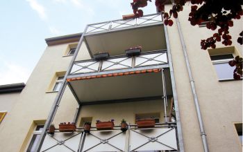 Balkonansicht eines Mehrfamilienhauses mit Blumenschmuck und modernem Wohnkomfort