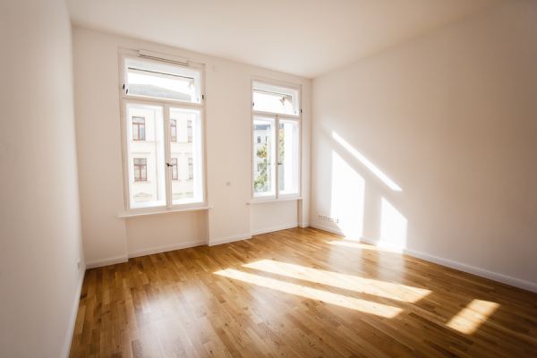 Lichtdurchflutetes Zimmer mit großen Fenstern und Parkett – modernes Wohnen im stilvollen Altbau