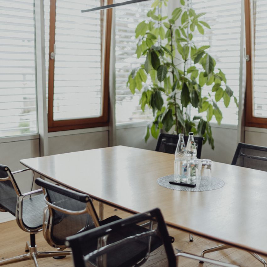 Moderner Besprechungsraum mit großen Fenstern, stilvollem Holzboden und freundlicher Atmosphäre