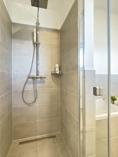 Modernes Badezimmer mit ebenerdiger Dusche, stilvollen Fliesen und einladender Badewanne zum Entspannen